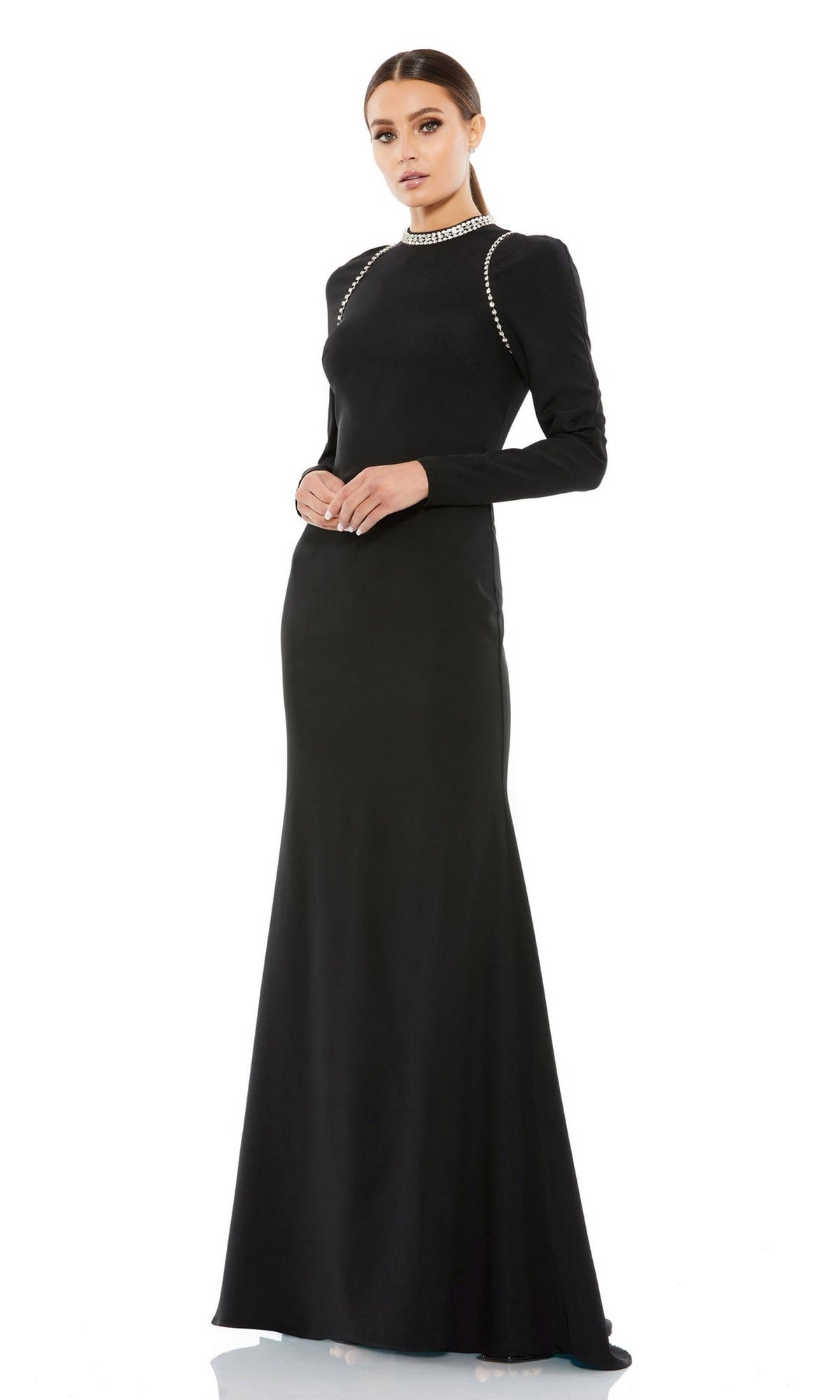 A woman poses elegantly in the Mac Duggal 26612 long sleeve black formal gown, adorned with jeweled accents on the shoulders and neckline, against a white background.